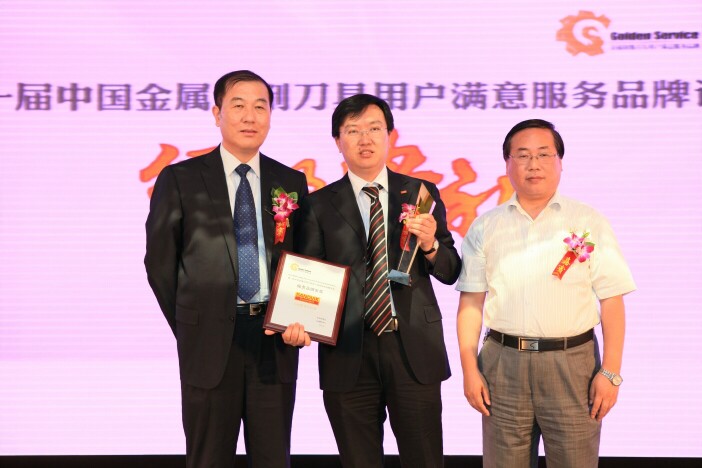 中国机械制造工艺协会机床工具专委会主任、东方电气集团中央研究院副院长王政（右一），中国刀协理事长、中国机床总公司总裁郝明为山特维克可乐满颁发“服务品牌金奖”奖牌和奖杯。 